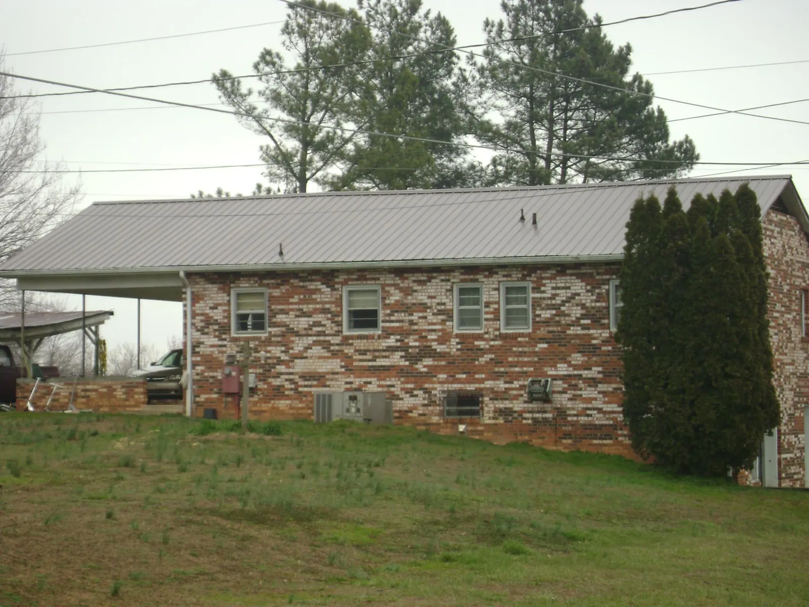 Gray metal roof on a brick split level home with a carport in Martin